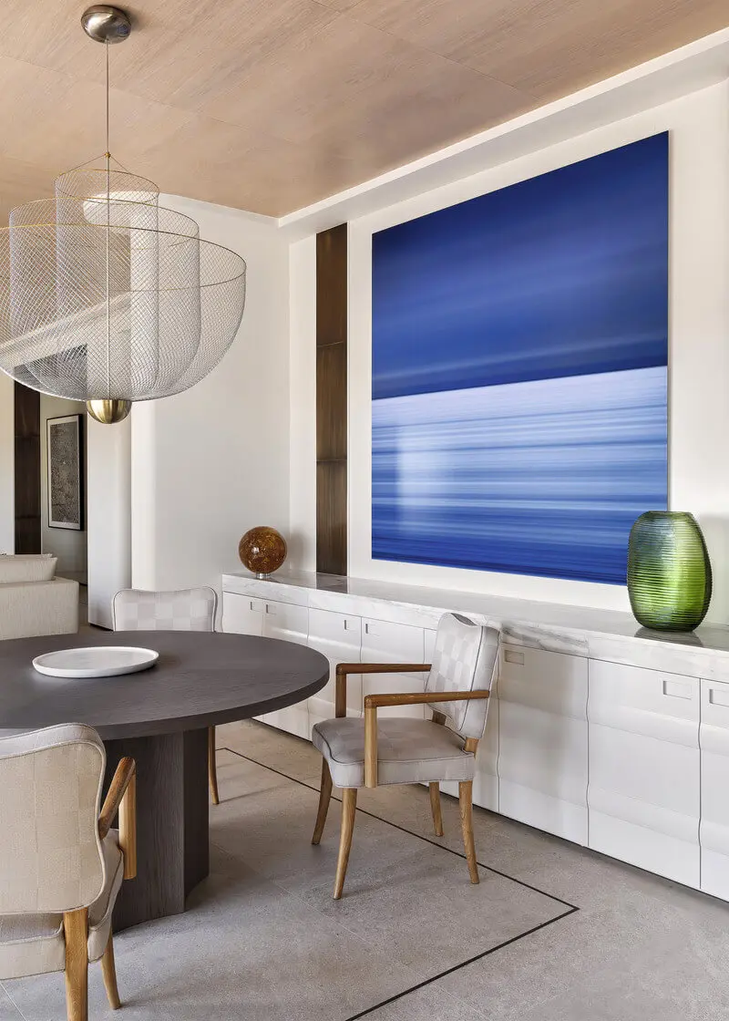 Large dining room featuring an oval table and a blue painting that reseambles the sea