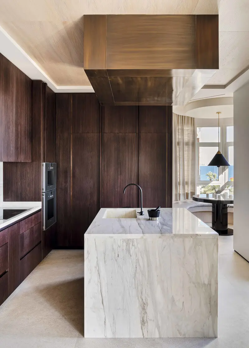 Kitchen with full wood panels all around and a big marble kitchen island