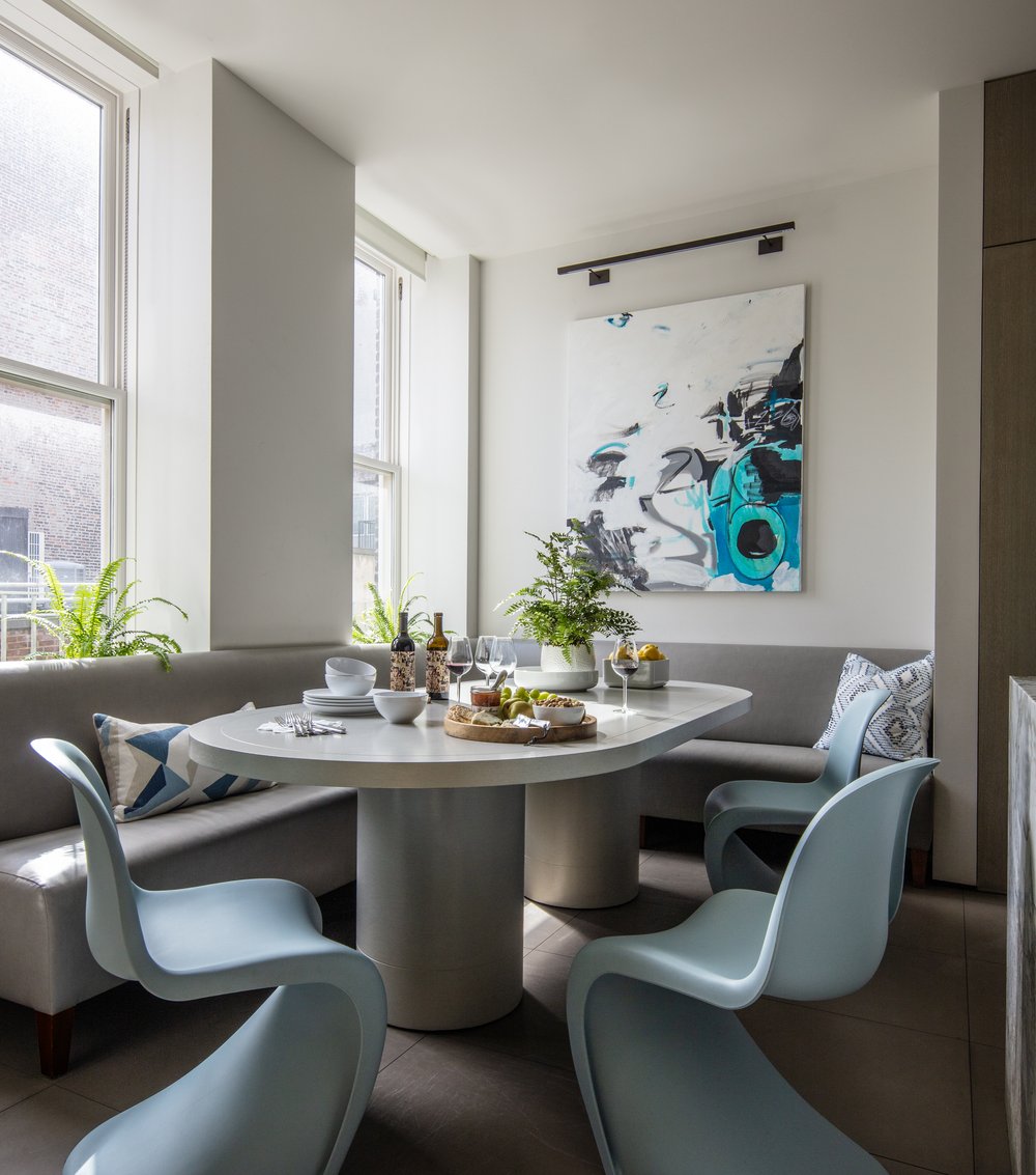 A contemporary dining room featuring blue chairs and a prominent painting.