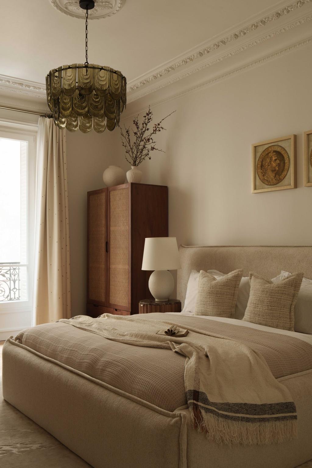 A timeless Parisian bedroom interior featuring a neutral color palette, textured bedding, and elegant wall art. The space is styled with a rattan wardrobe, ceramic table lamp, and soft drapery, creating a warm and sophisticated atmosphere ideal for modern living. Perfect inspiration for classic Parisian interior design lovers.