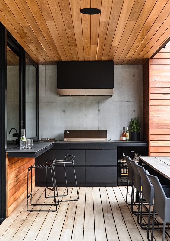 A mix of black and wood furniture in a outdoor kitchen