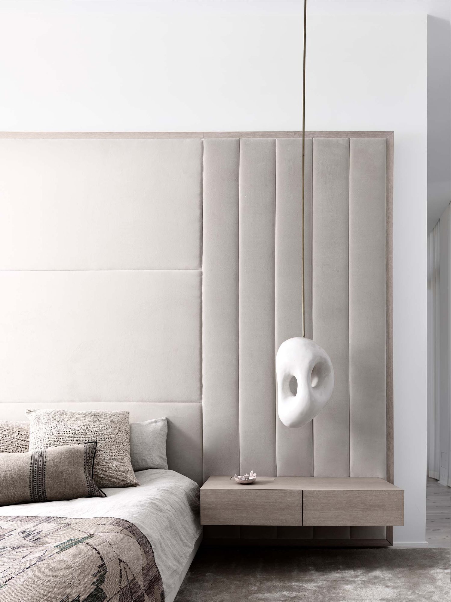 A modern bedroom featuring a stone sculptured suspension lamp