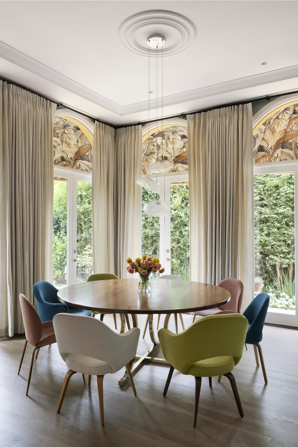 Circular dining table and a set of colorful chairs around it