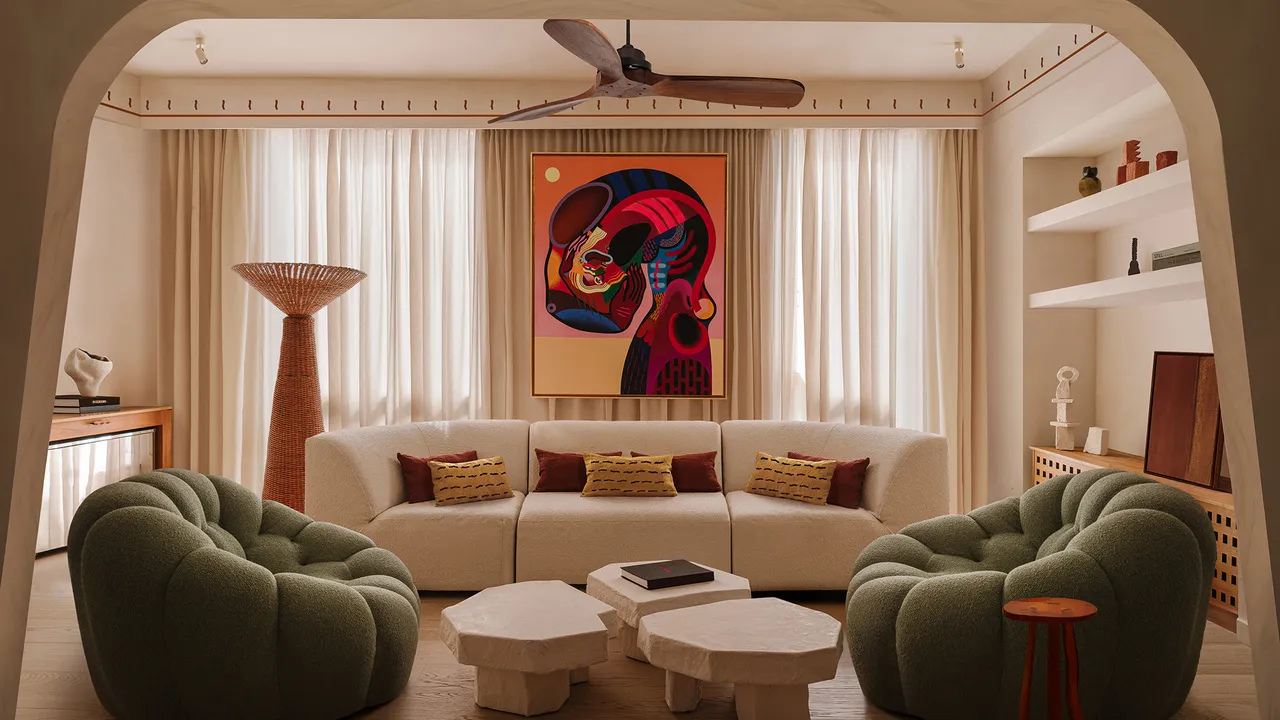 A 969-Square-Foot Small Apartment Filled With Sunlight, a living area with unique interior design ideas, designer´s armchairs, artwork, and stone coffee tables.