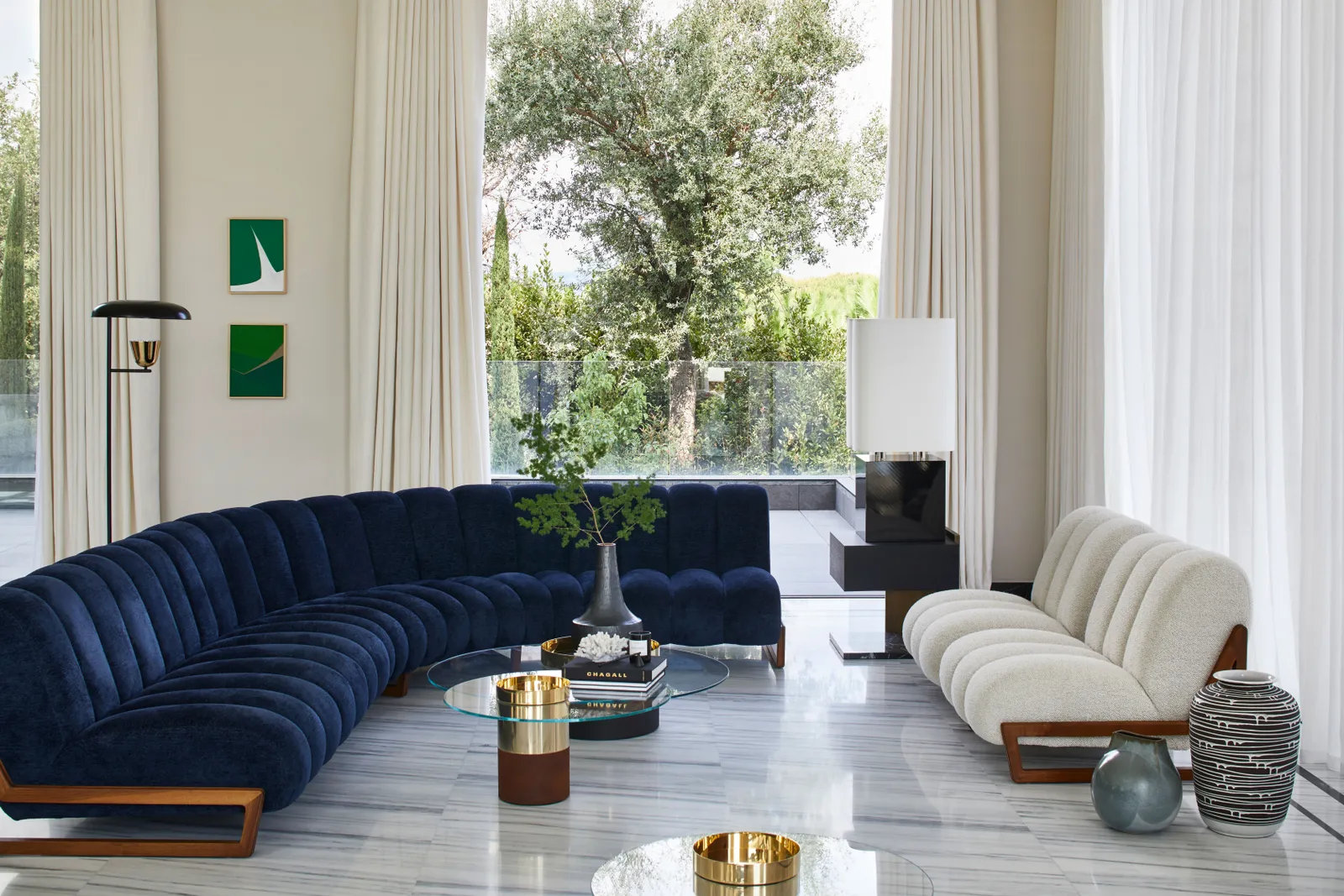Living room featuring a modern blue curved sofa and two cream armchairs 