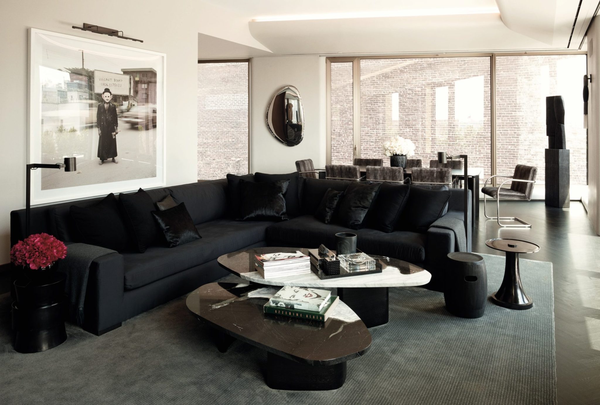 A modern living room featuring a plush black sofa and two curvy center tables