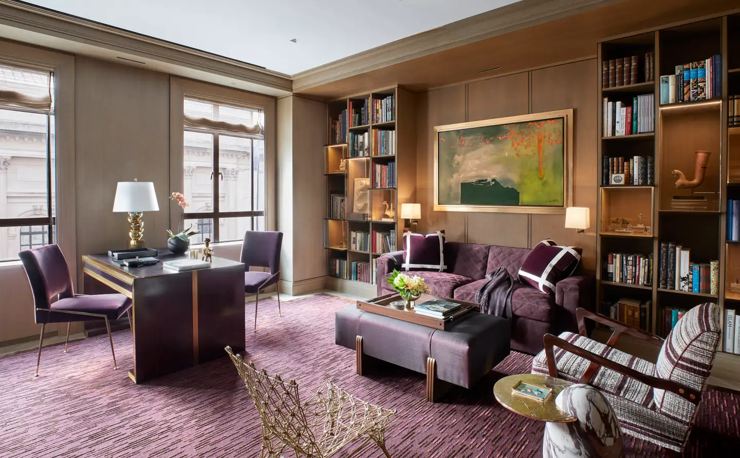 Sophisticated study room in rich purple and burgundy tones, featuring a unique artwork on the wall, exclusive rug, comfortable desk and seating area, and built-in bookshelves