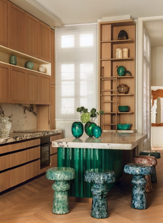 A central island wrapped in green ceramic tiles injects vibrant energy into the otherwise neutral scheme. Paris apartment