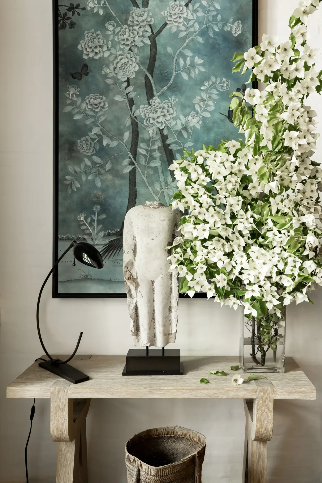 Table with a flour vase and a painting of flowers behind it