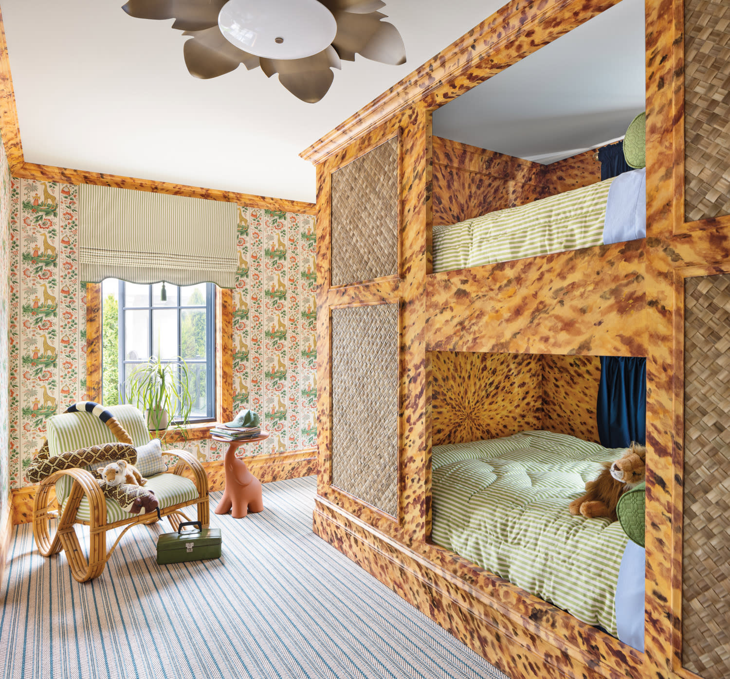 Children’s bedroom featuring custom faux tortoiseshell bunk beds, vintage floral wallpaper, and green striped bedding. A playful side table and sculptural toy complete the whimsical, eclectic space.