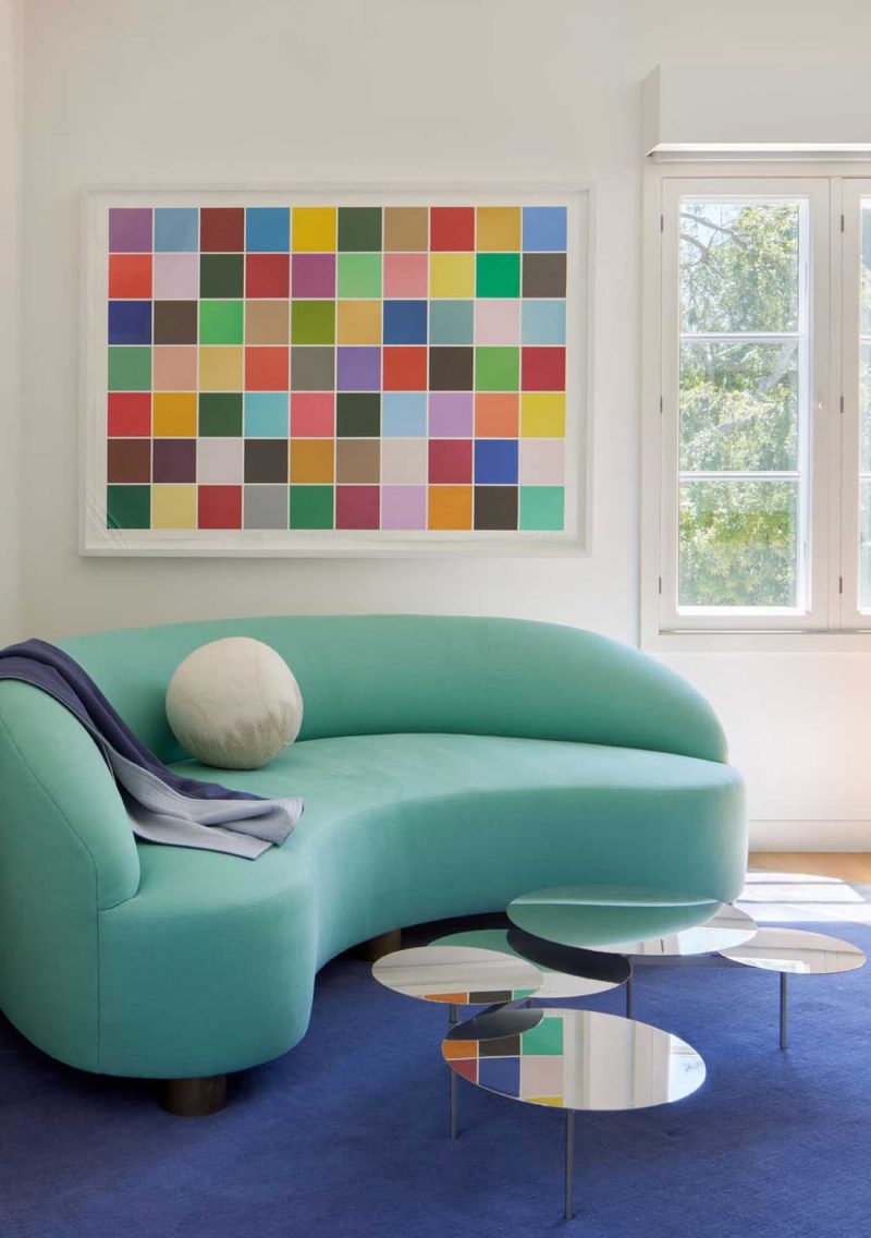 Living room featuring a curvy aquamarine sofa and a colorful geometric abstract painting