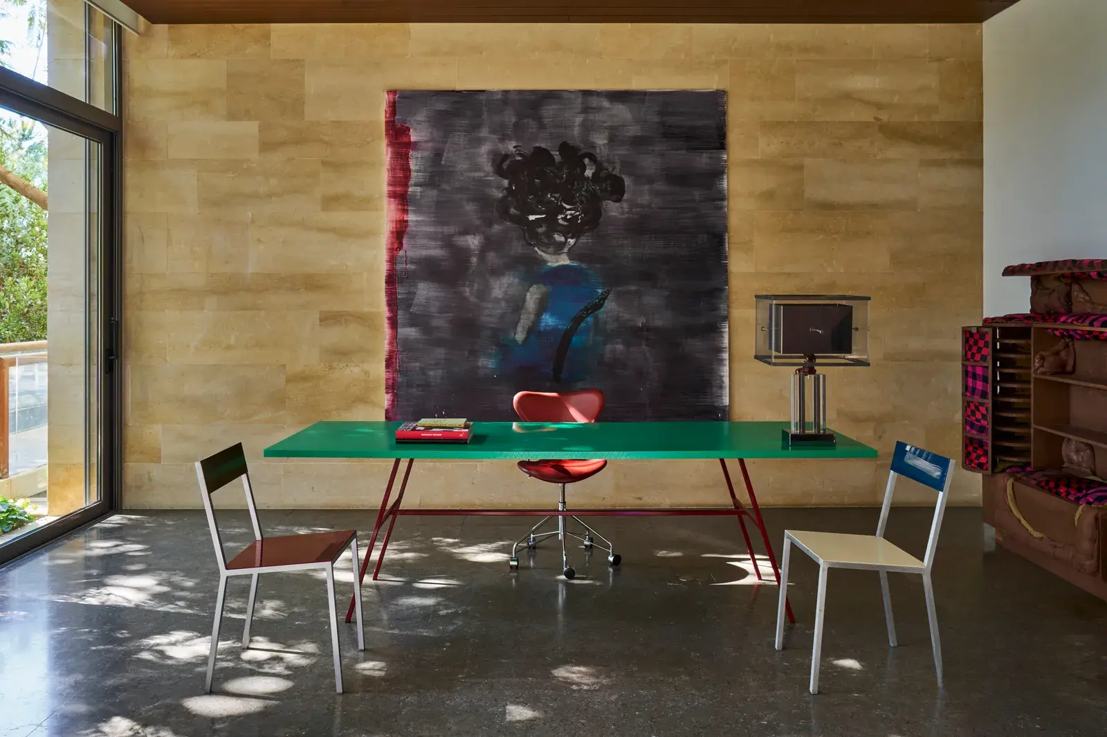 Working space with a green-colored desk, cozy seating, and a large canvas by a well-known artist in the background