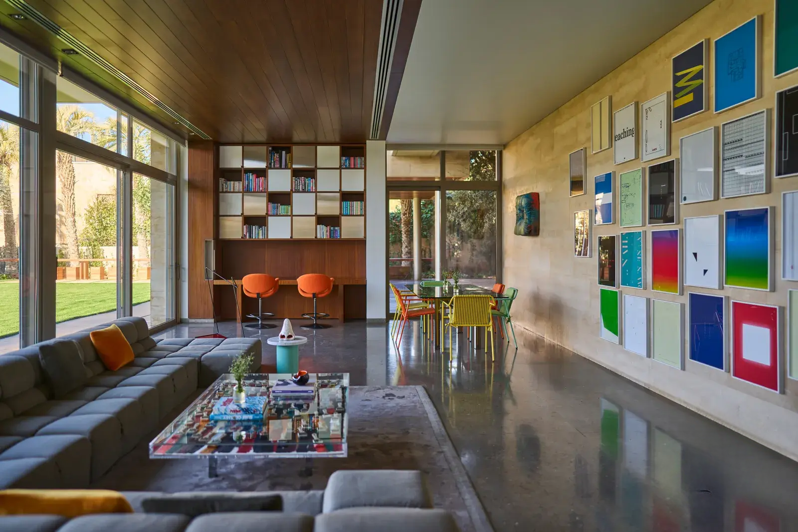 Living room filled with art objects, canvases on the walls, bookshelves, a large cozy sofa, and a coffee table by a well-known designer, with plenty of natural light and spaciousness.