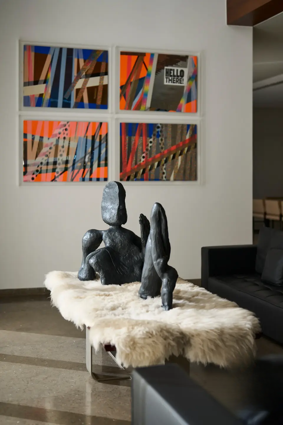 Art piece by a renowned artist composed of four different canvases, with a unique designer coffee table featuring a metal sculpture on it in the living room.