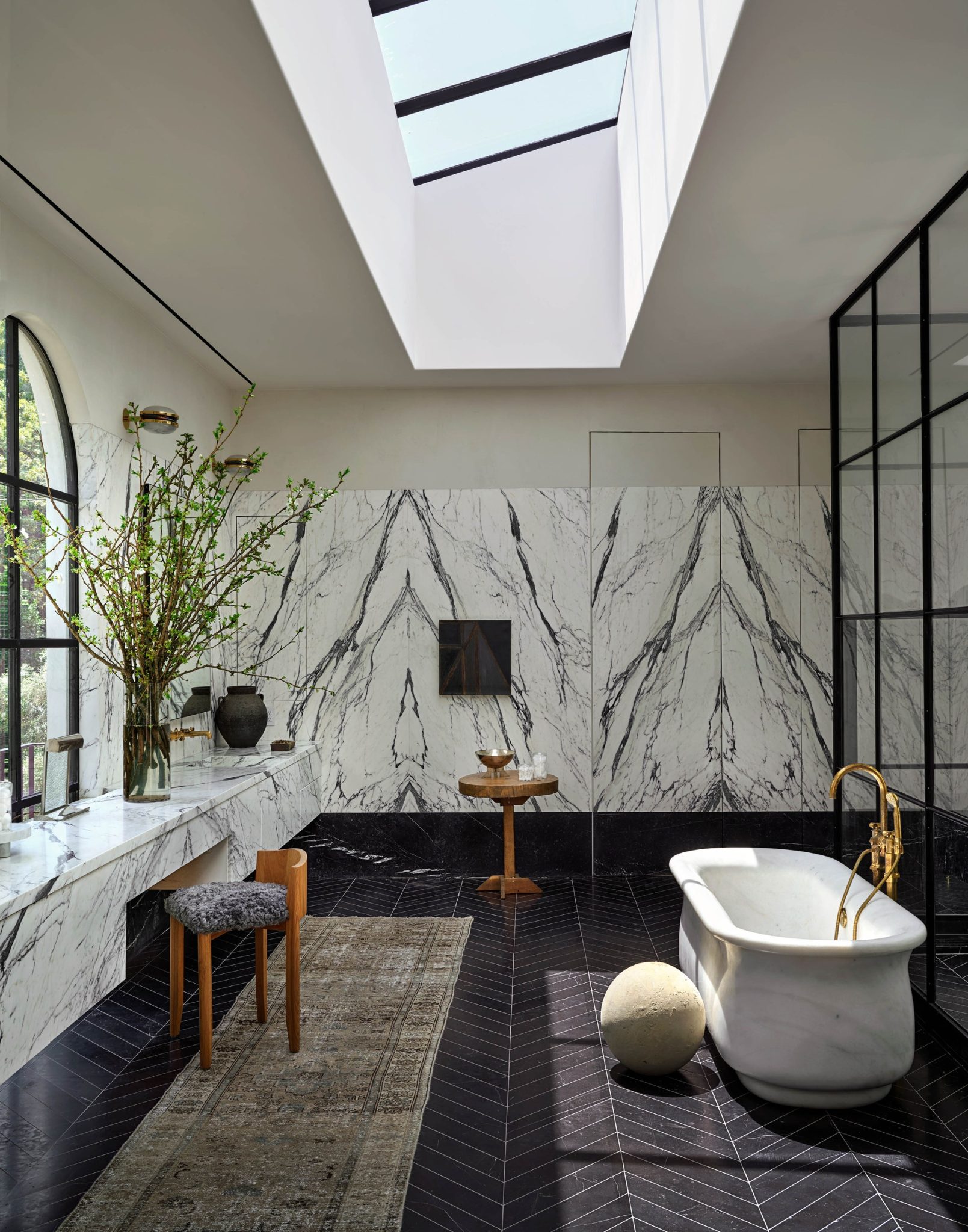 primary bathroom with a custom marble tub and custom nero marquina herringbone tile flooring