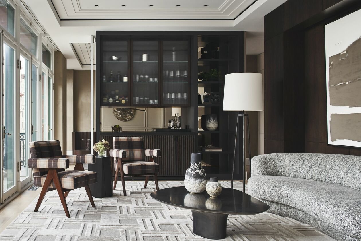 Living room featuring a modern geometric pattern rug that contrasts with two modern armchairs upholstered in a vintage fabric