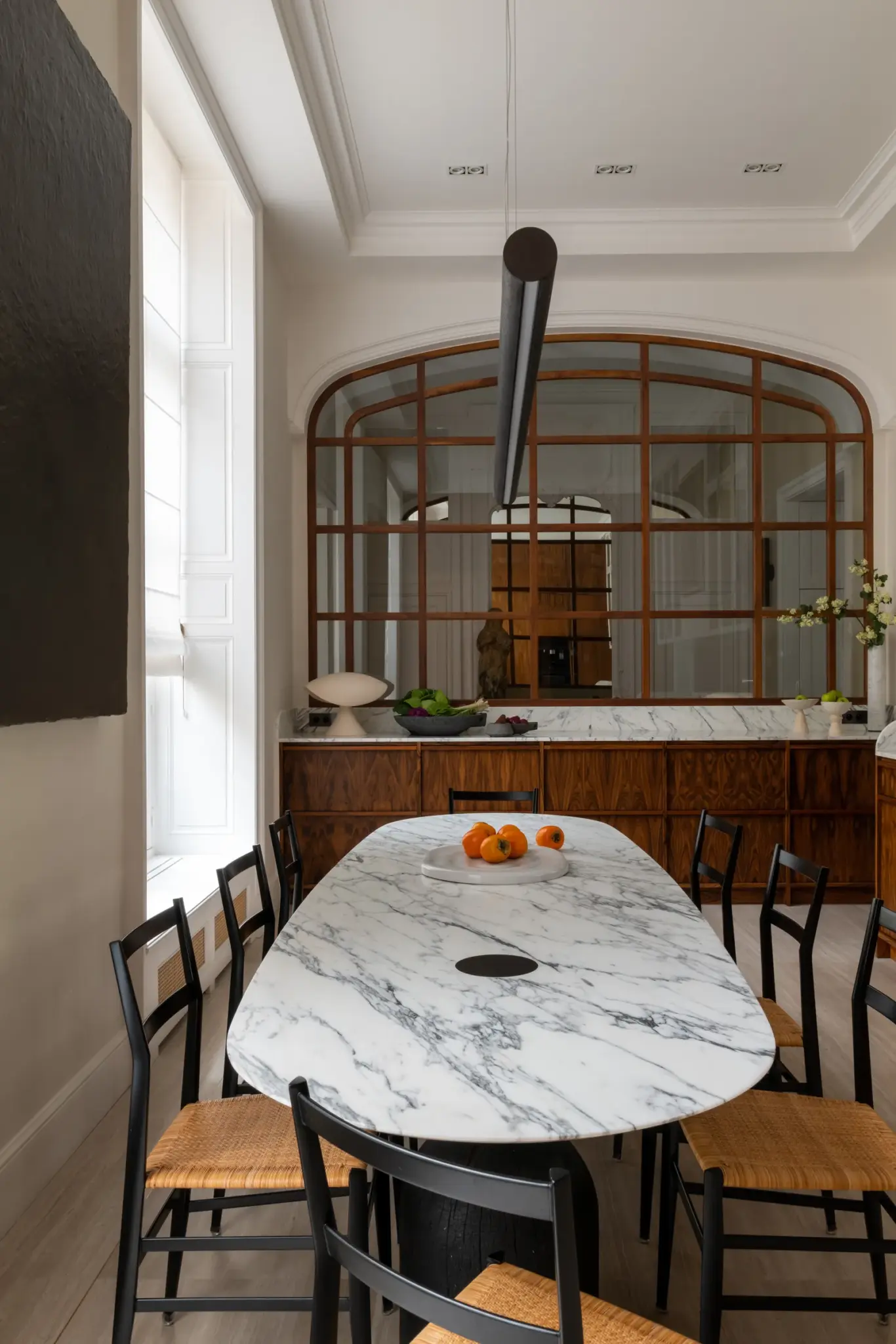 Marble table and handmade chairs in the kitchen, with a large window that floods the space with natural light.