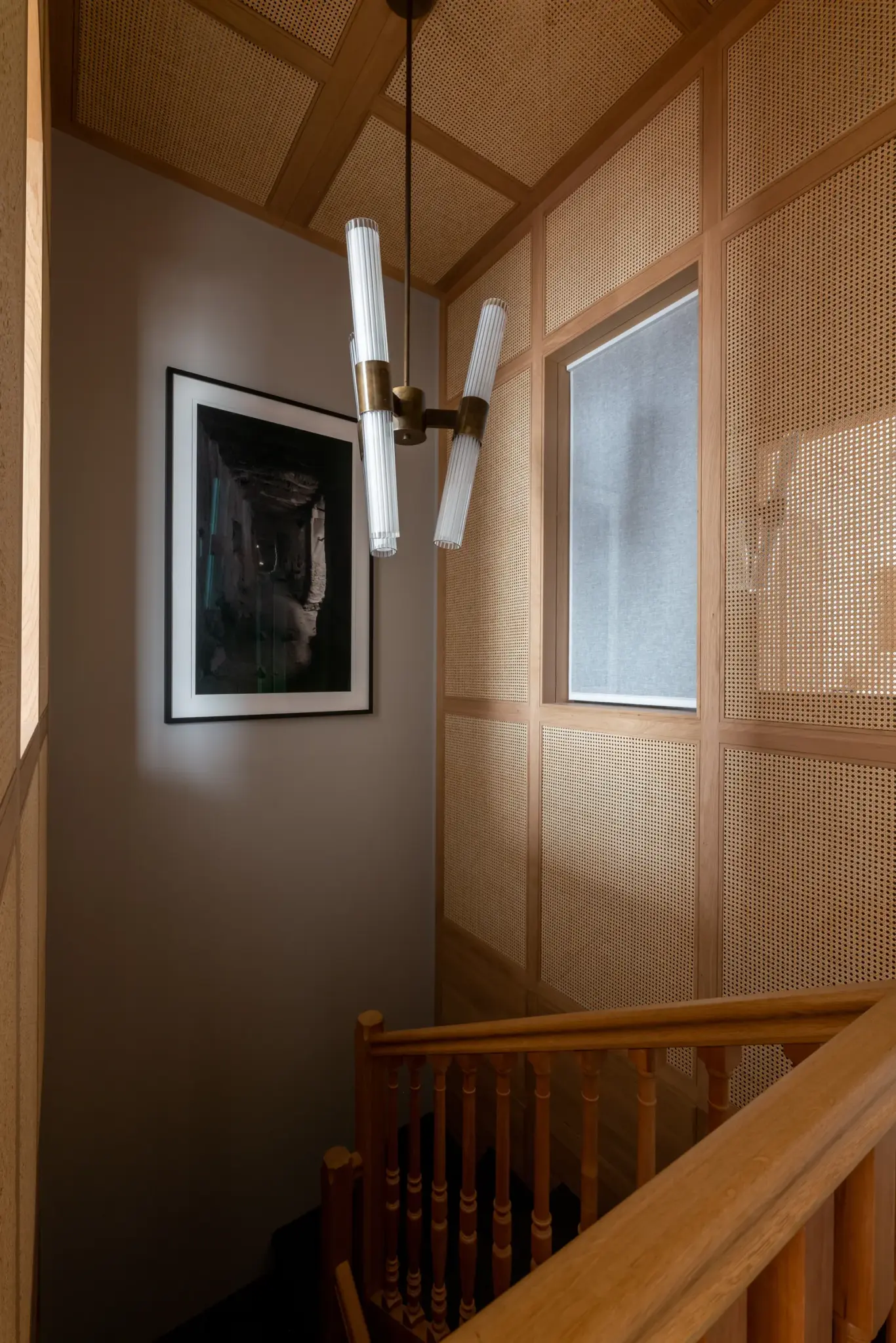A ladder leading to the second floor of the Paris apartment, complemented by hanging lamps, wooden elements, and sleek wooden railings