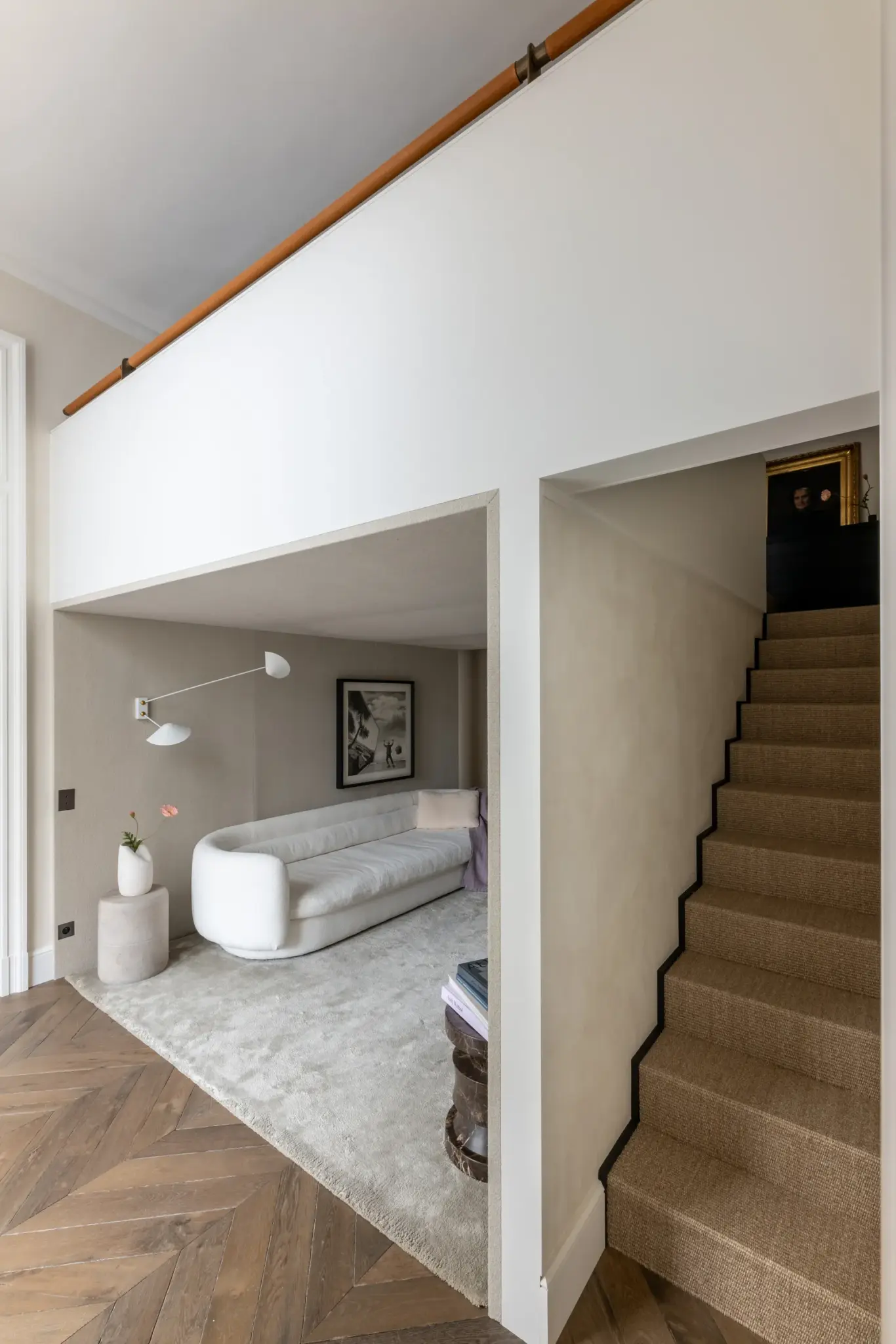Studio sofa area featuring a Limited Edition rug, stairs leading to the second floor, and abundant natural light.