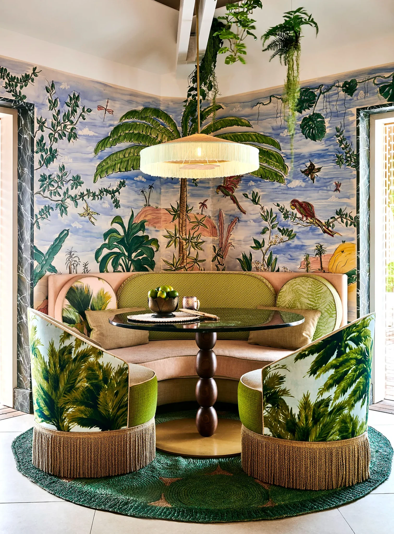 Armchairs and sofa upholstered in tropical print matching the wallpaper behind them