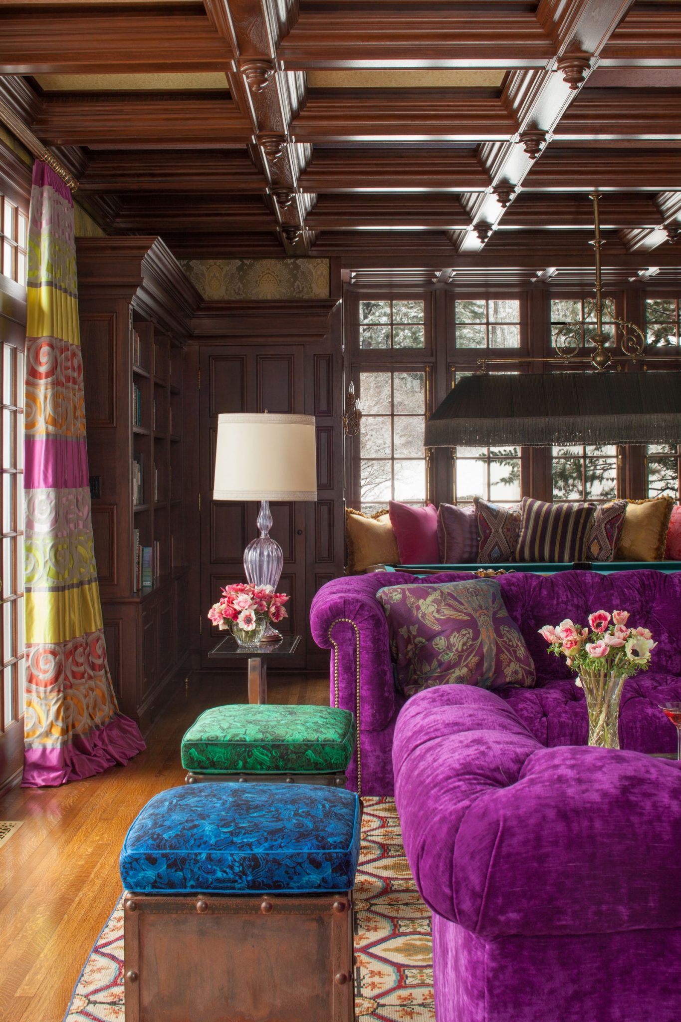 library room with lined in walnut shelves and anchored by bespoke sofas upholstered in vibrant purple velvet.