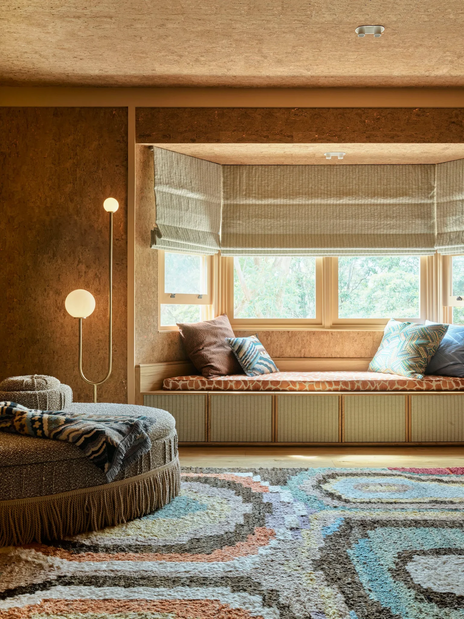 Cozy corner of the master bedroom featuring a pouf upholstered in tan fabric