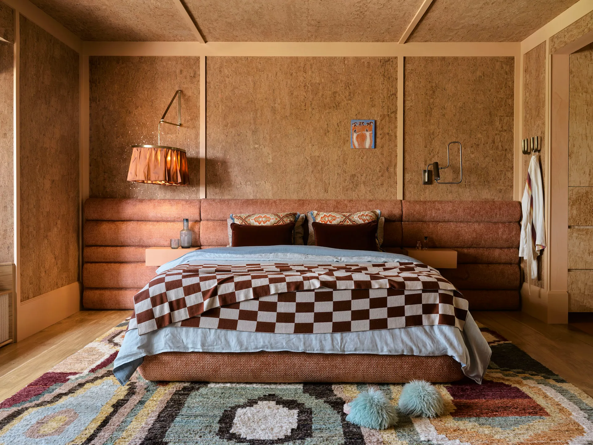 Main bedroom featuring a custom upholstered bed which complements the cork wallpaper on the walls