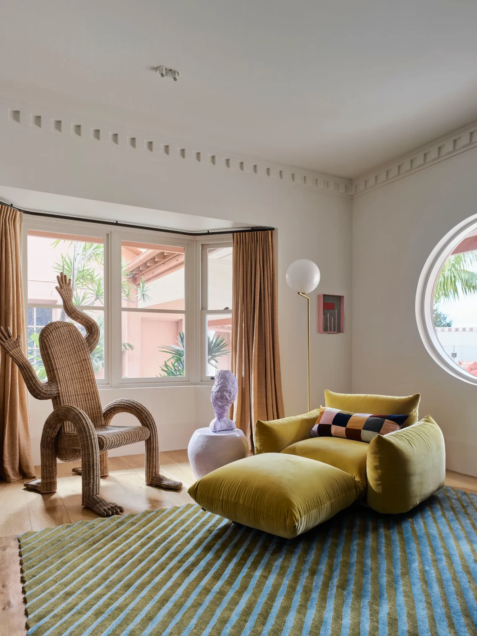 Living room featuring a yellow armchair and matching stool, an eclectic chair and a blue and brown striped rug