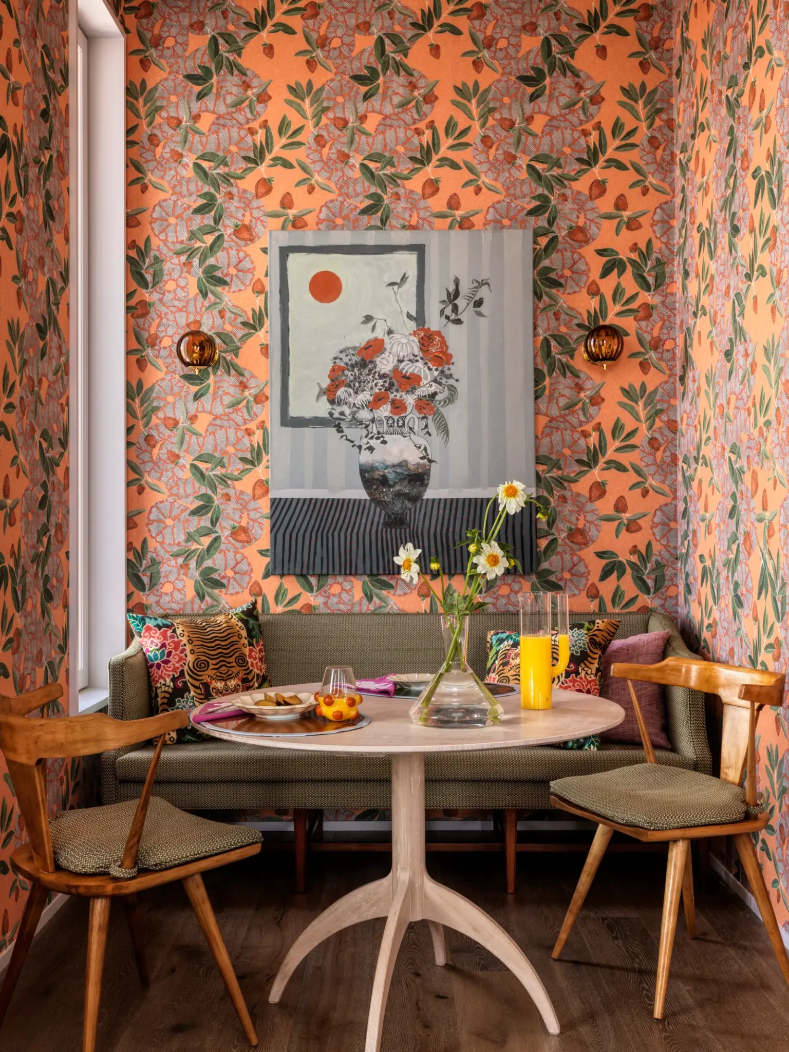breakfast corner with bold floral wallpapers, wooden round table with set of chairs and 2 seats sofa, art work on a wall
