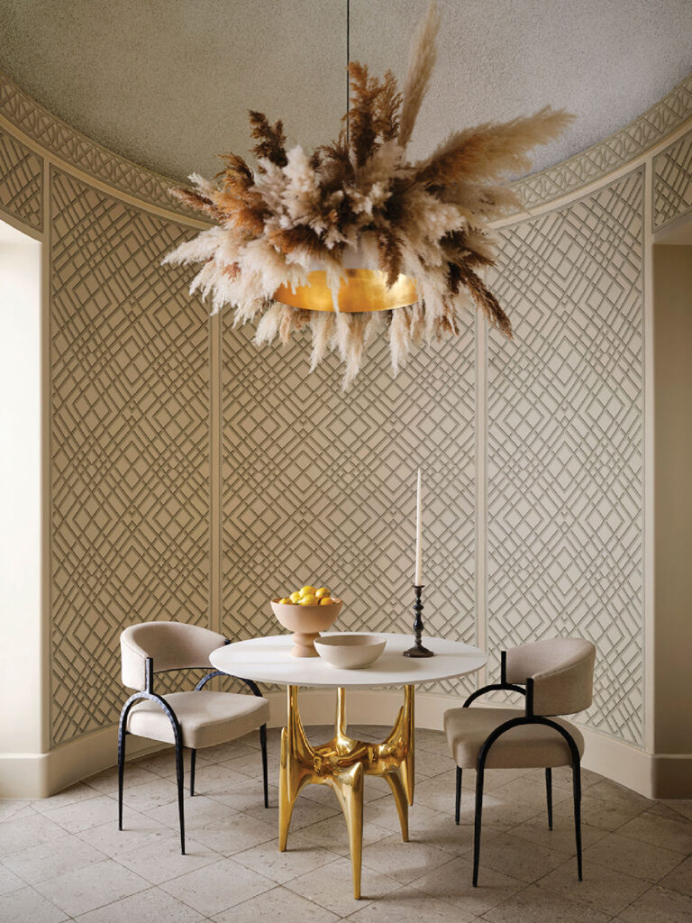 Luxury Interior Design,A round table with a gleaming gold base becomes the jewel of space, paired with curved upholstered chairs. Above, a custom pampas grass chandelier floats like a soft cloud, casting a warm glow. 