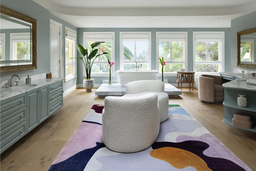 An opulent bathroom with a colorful rug and a cream sofa at it center