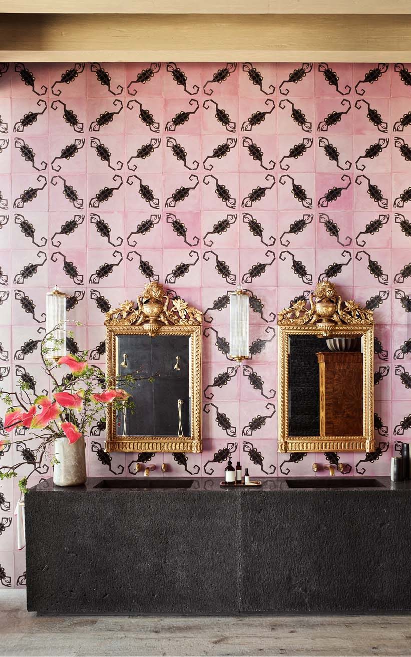 A black stone counter and a tropical pink wallpaper in the bathroom
