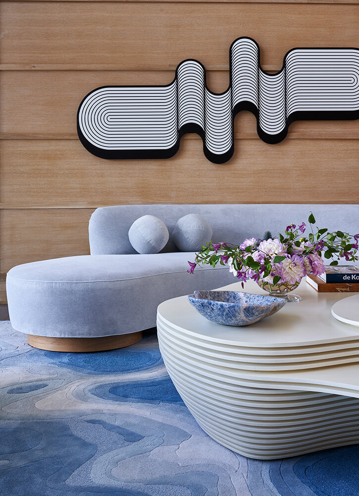 Modern interior design project by Michelle Gerson in Hamptons, New York City. The image pictures a living room in white and shades of blue with a modern coffee table and a modern blue rug.