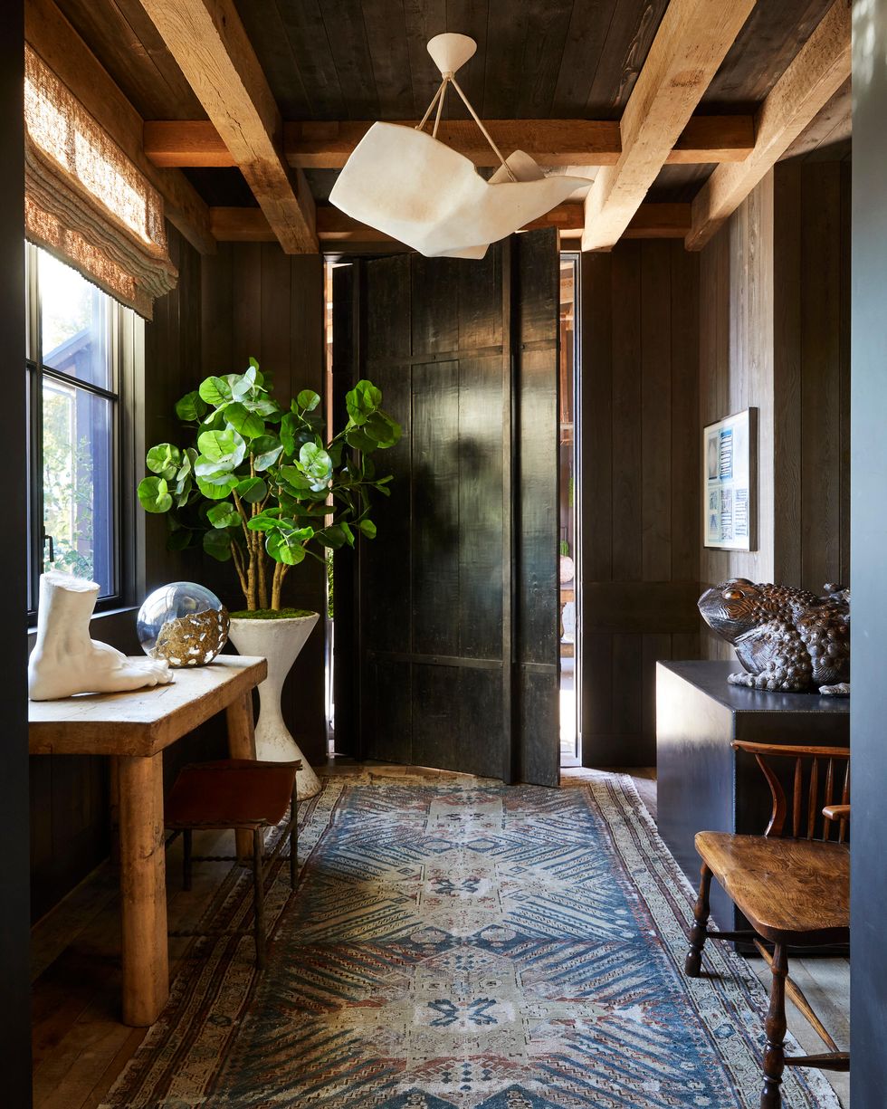 This entryway combines rustic charm with modern elegance, featuring exposed wooden beams and dark-paneled walls that create a warm and inviting atmosphere.