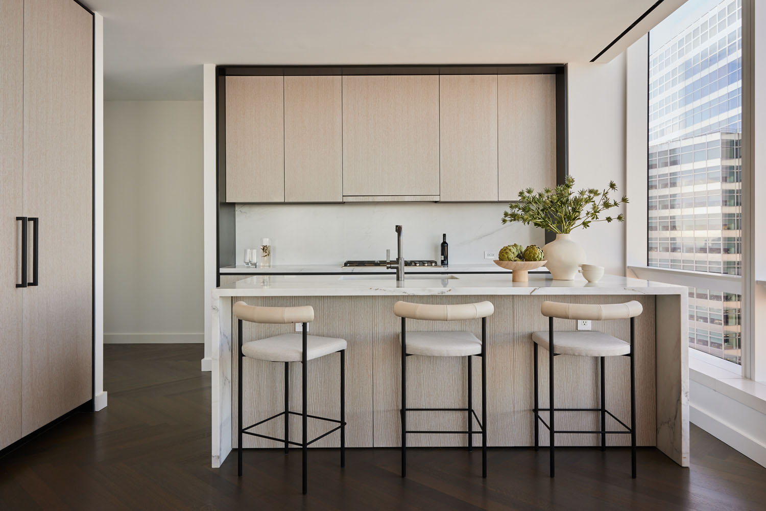 Modern kitchen in neutral tones featuring upholstered bar chairs