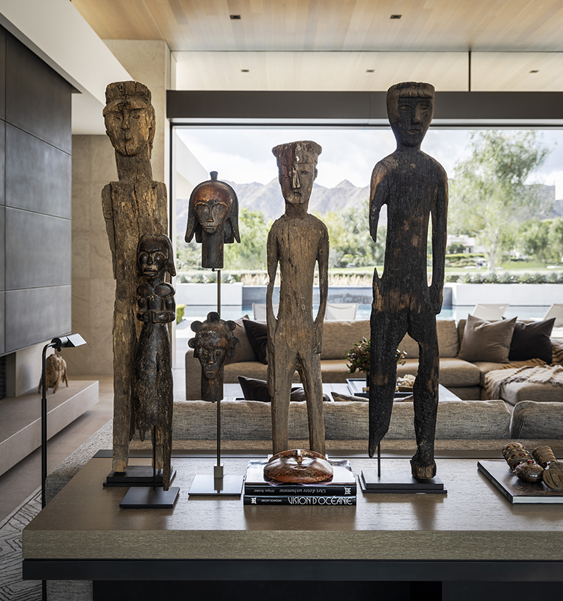 a large-scale console that holds a formation of towering antique African wood figurines and faces