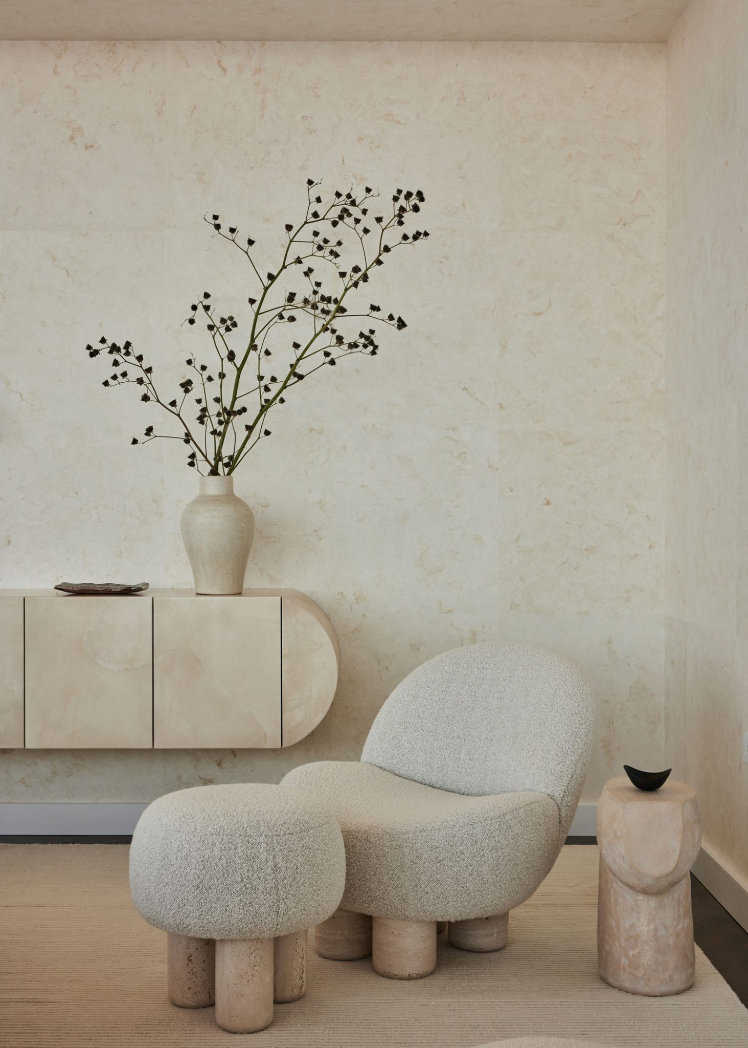 Modern living room in neutral tones featuring a modern beige armchair and matching stool