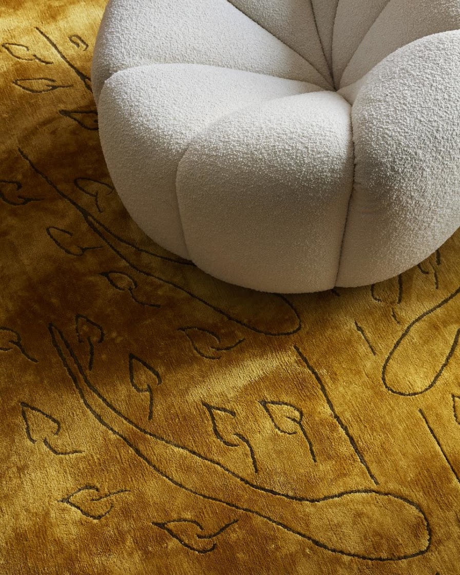 A modern curvy white armchair on top of a yellow musturdy carpet