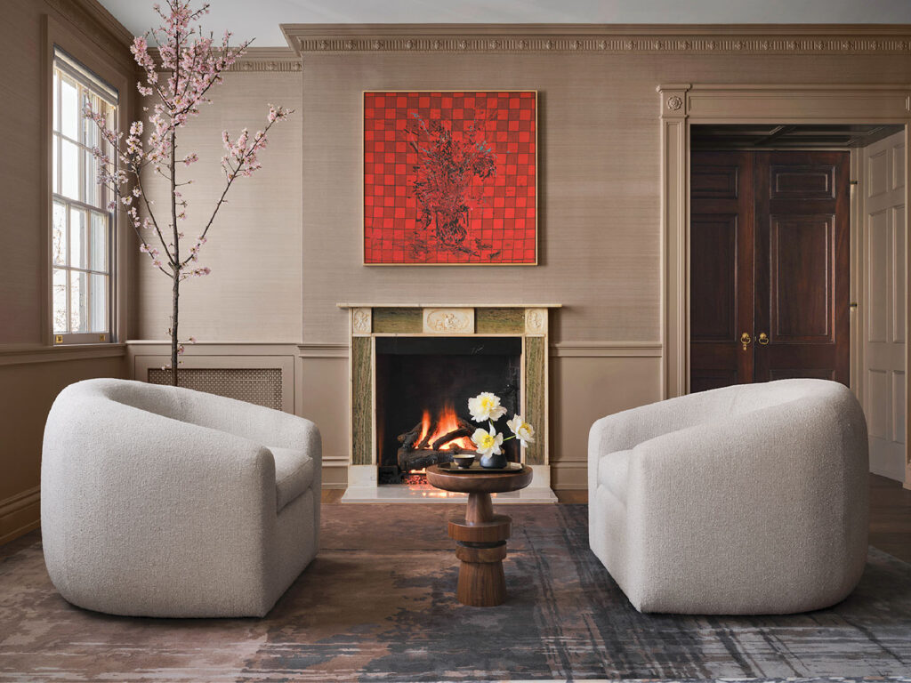 In the salon, classic architecture meets modern ease. A carved stone fireplace anchors sculptural chairs arranged for quiet conversation. 