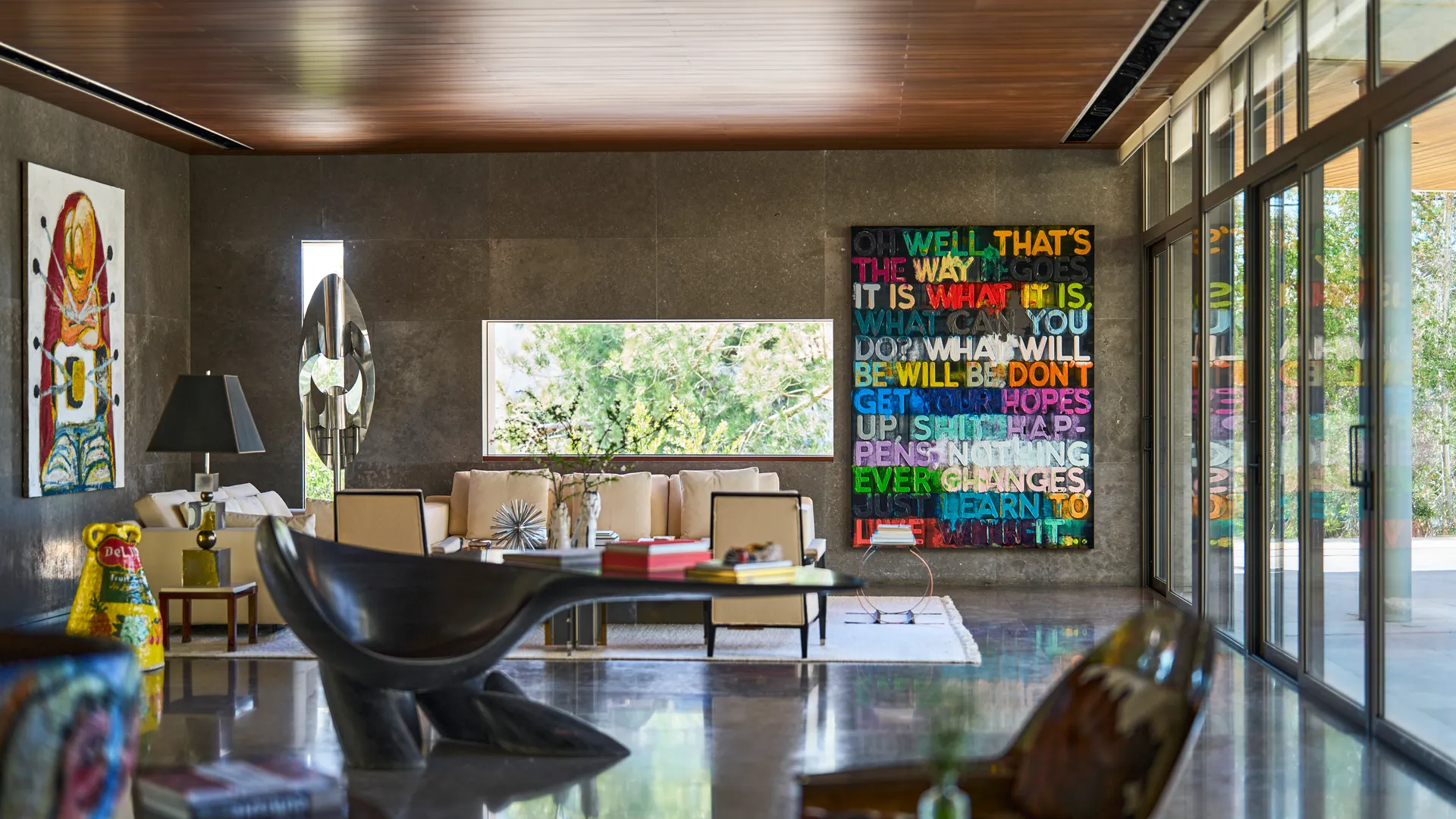 Panoramic floor-to-ceiling windows allowing natural light to fill the villa, surrounded by lush greenery, with unique furniture pieces and artwork adorning the walls