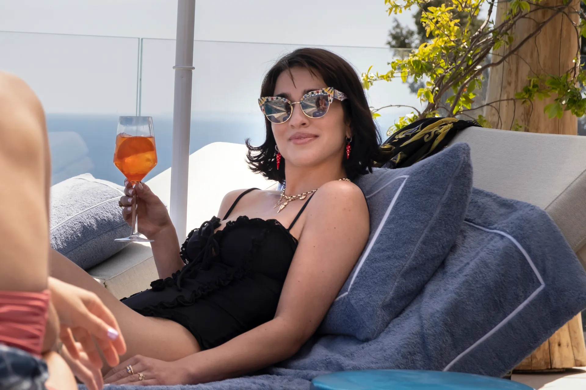 Lucia (Simona Tabasco) sipping a cocktail by the pool