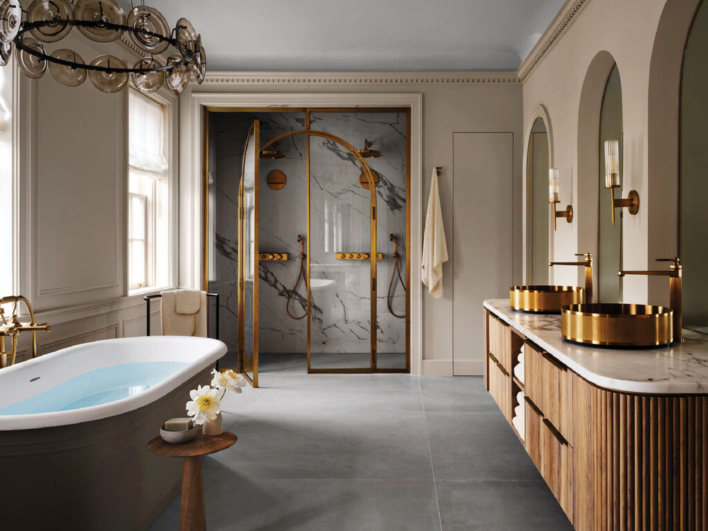 This bathroom reimagines everyday routines as moments of luxury. An arched bronze-framed shower enclosure sets a glamorous tone. 