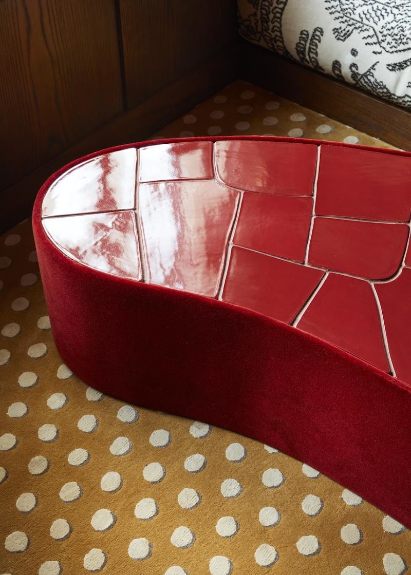 Curvy red center table on top of a yellow carpet with white polka dots